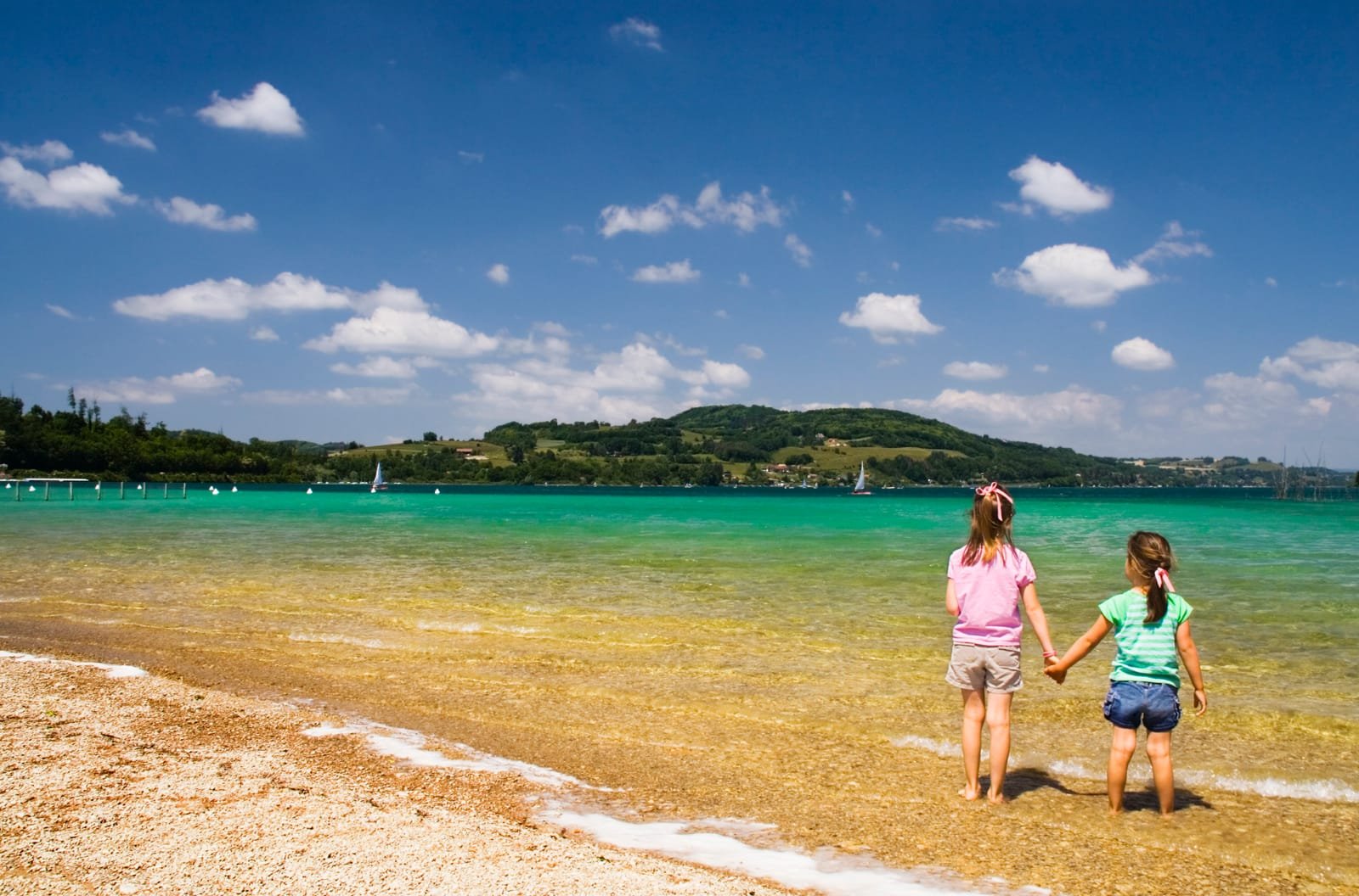 85252704_two-young-girls-standing-on-the-beach-watching-a-swan-under-a-brilliant-sky-lac-de-paladru-near-charavines-france